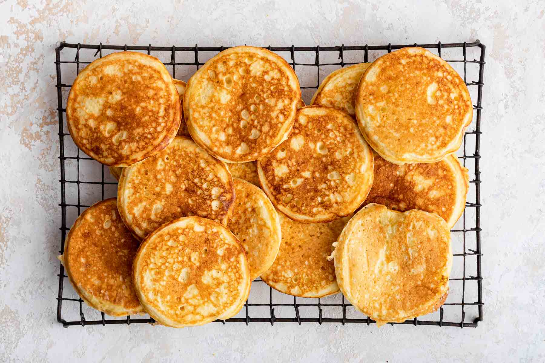 Horizontal image of round pancakes recipe on wire cooling rack.