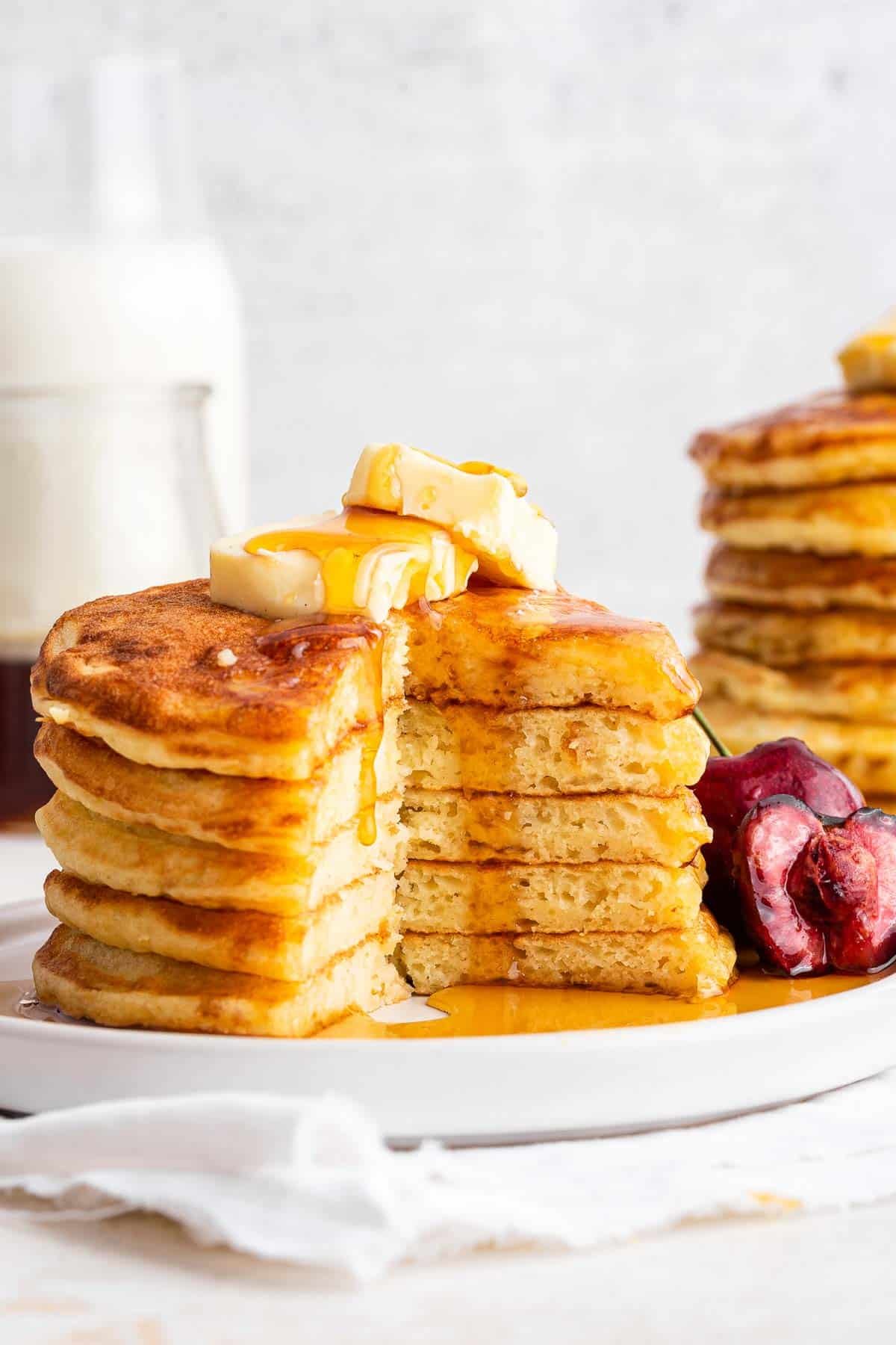 Stack of pancakes with one huge bite missing and butter nd syrup on top.