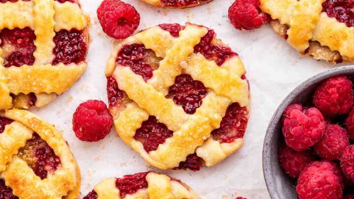 Overhead shot of raspberry pie cookies, round circles like mini pies with red berries.
