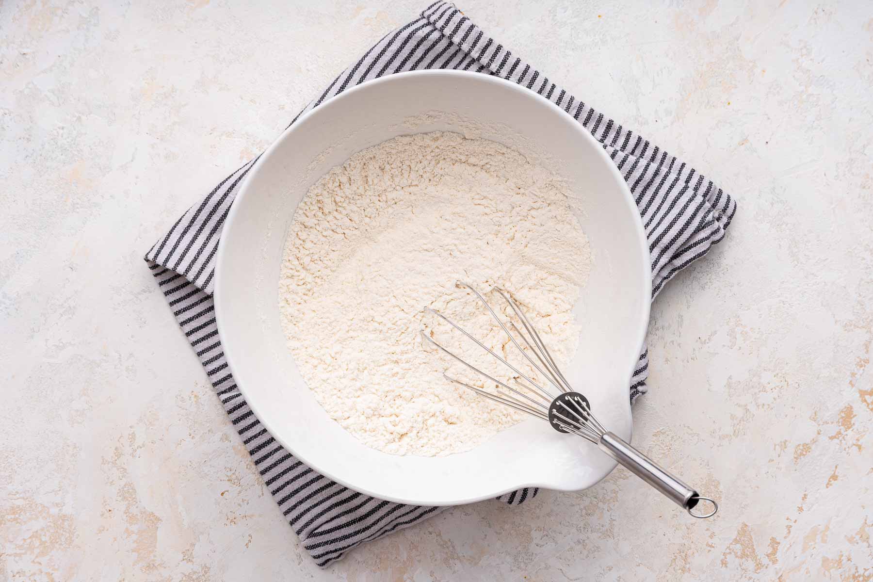 Flour, baking soda and salt whisked in a white bowl.