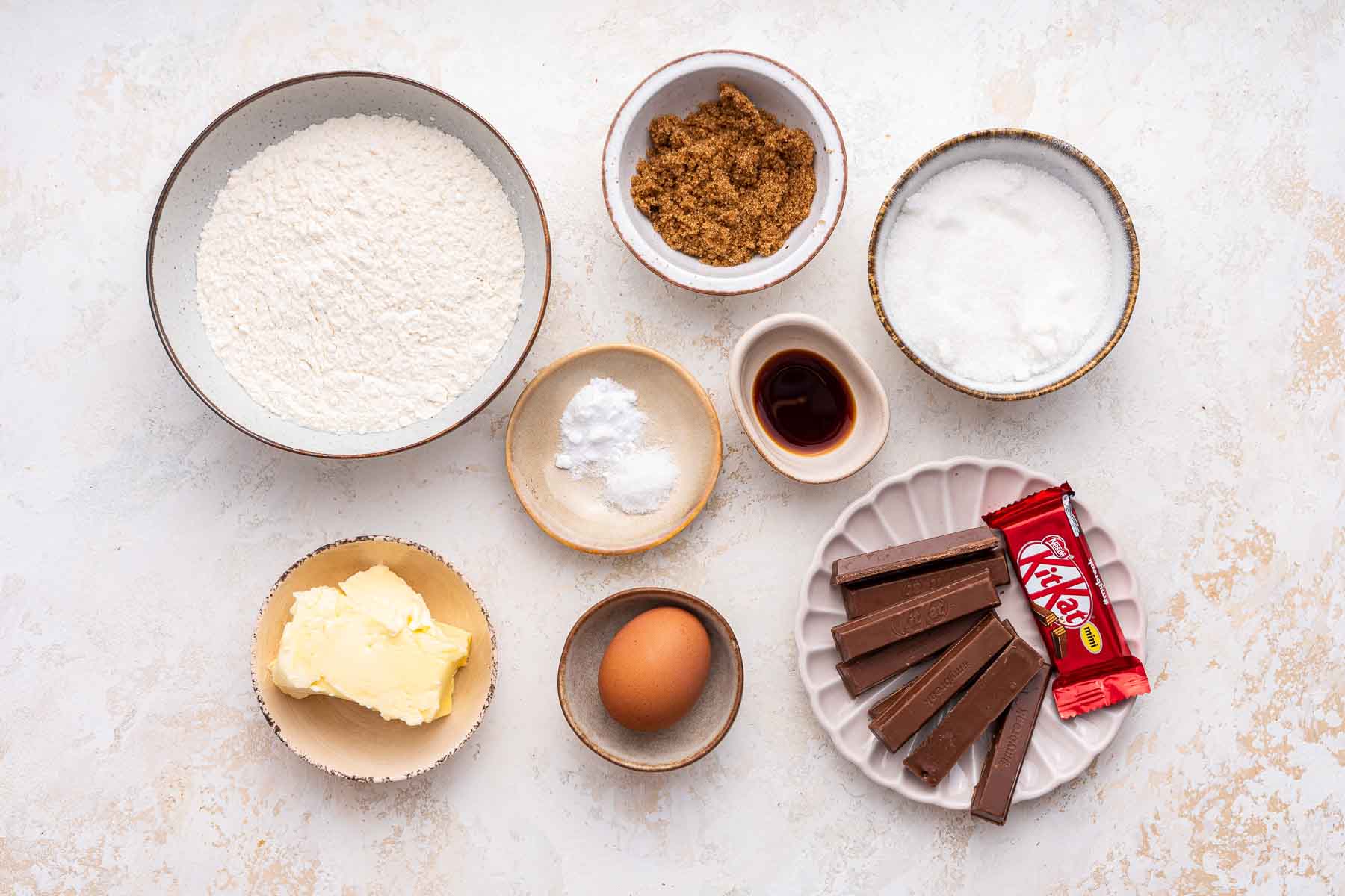 Ingredients for baking, including chocolate bars on white counter top.