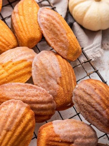 Close up shot of pumpkin madeleines on cooling rack with pumpkin on the side.