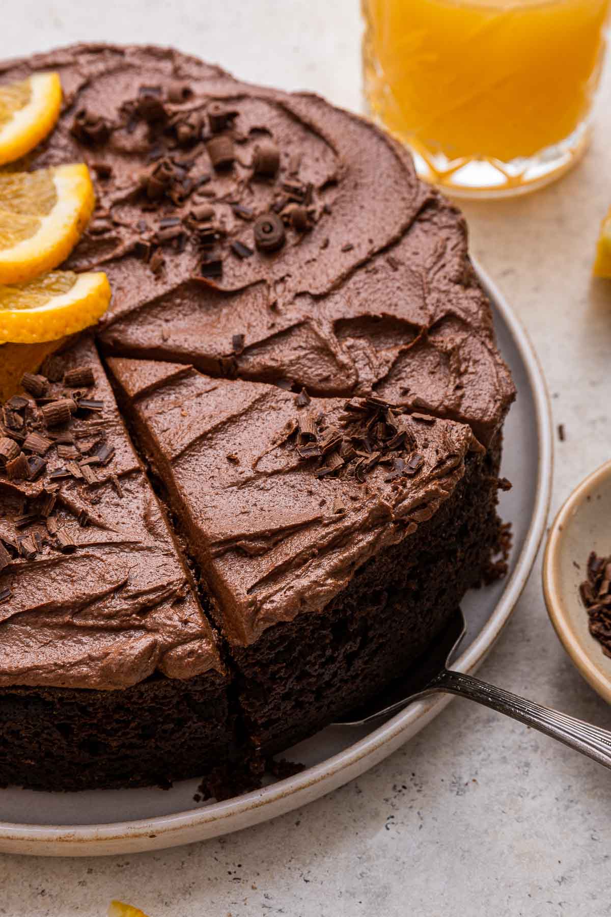 Close up of one layer chocolate orange cake with fudge frosting and a slice being cut.