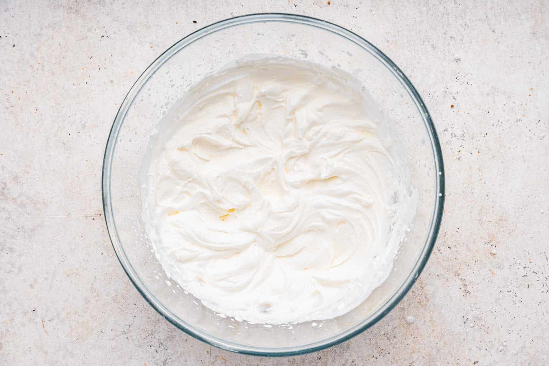 Bowl of freshly whipped cream on marble surface.