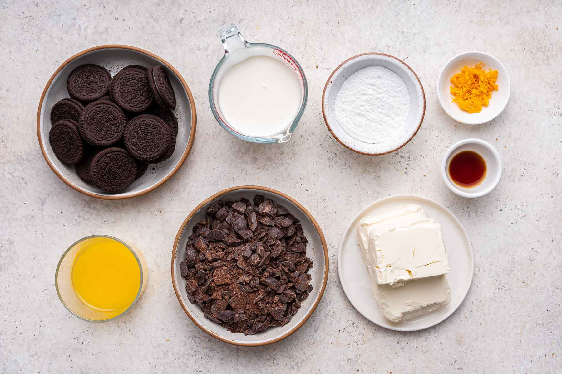 Small bowls of chocolate, cream cheese and orange juice on marble counter.