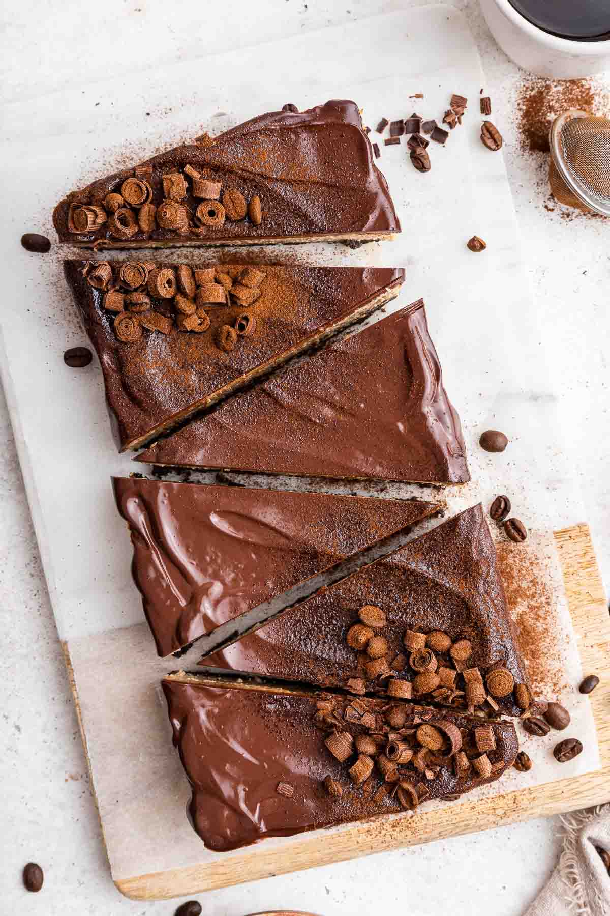 Six slices of a chocolate dessert decorated with ganache and chocolate curls.