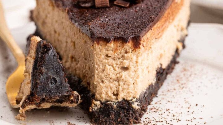 Up close shot of slice of coffee cheesecake decorated with chocolate curls.