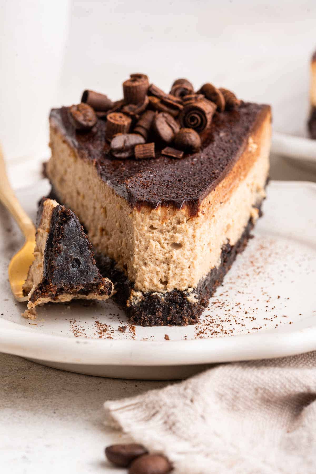 Up close shot of slice of coffee cheesecake decorated with chocolate curls.