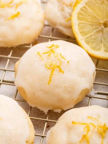 Lemon ricotta cookies close up with lemon slice on side.