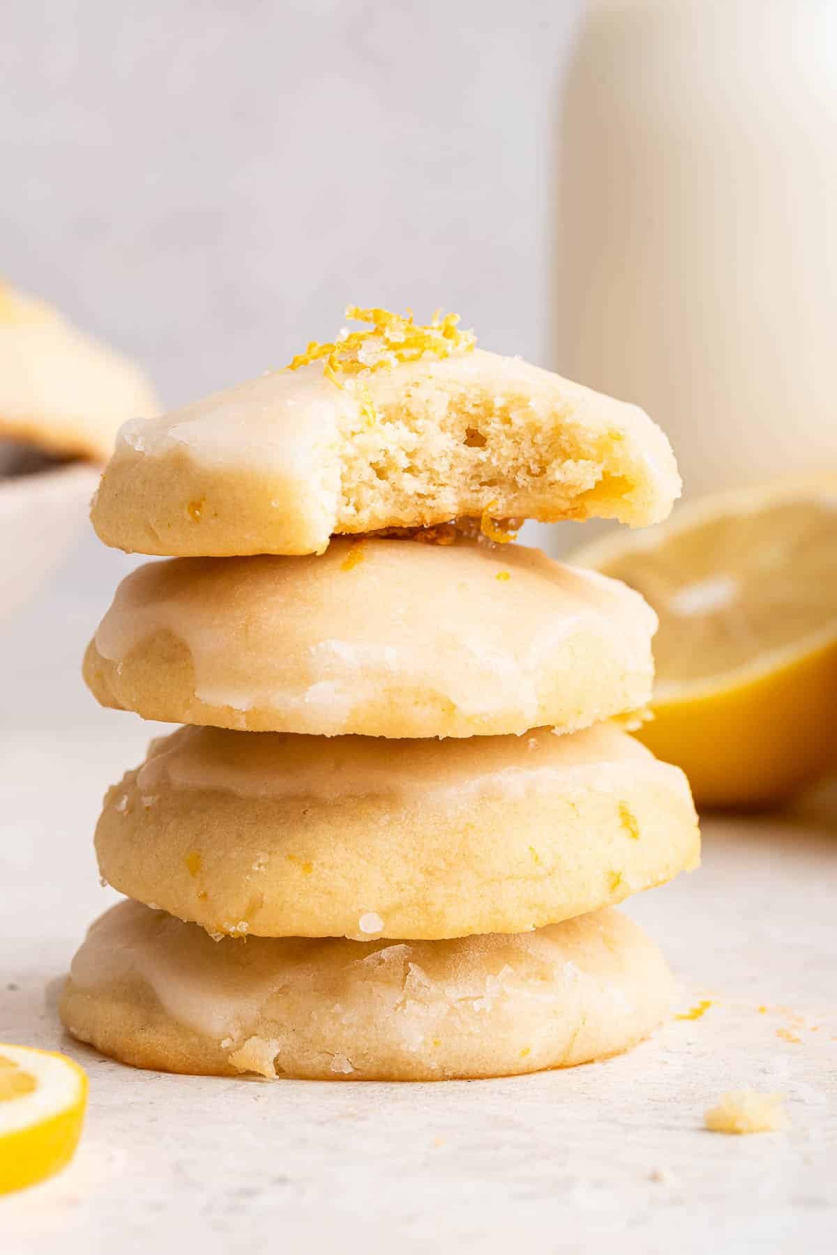 Stack of 4 yellow cookies on top with a bite missing from one.