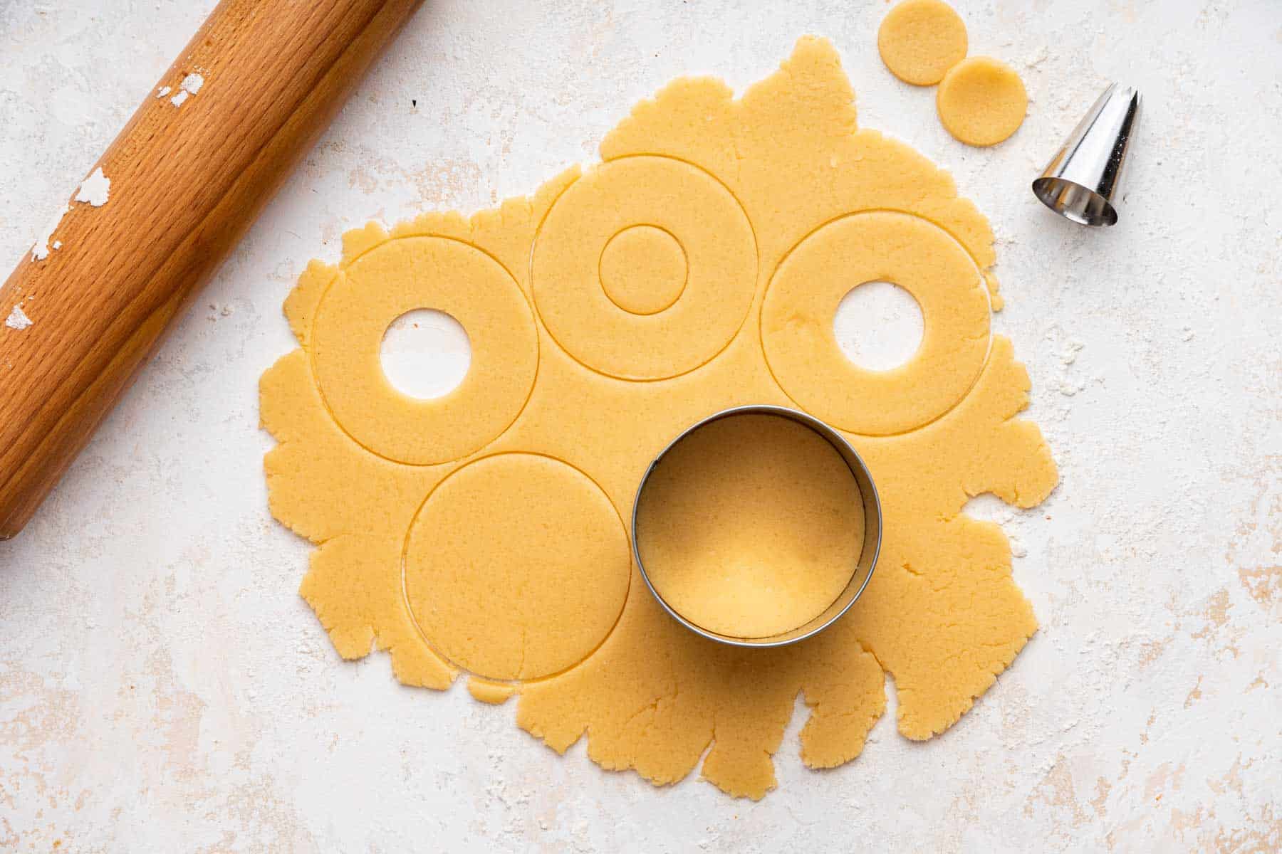 Using round cookie cutters on sugar cookie dough with rolling pin.