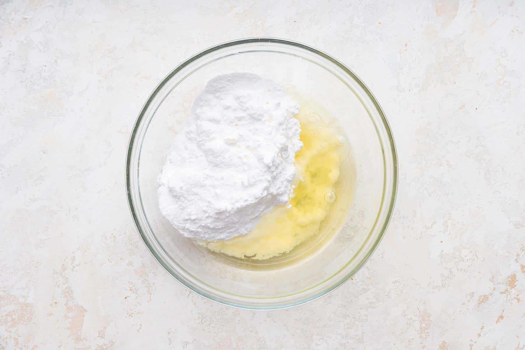 Egg white, powdered sugar and lemon juice in clear glass bowl.