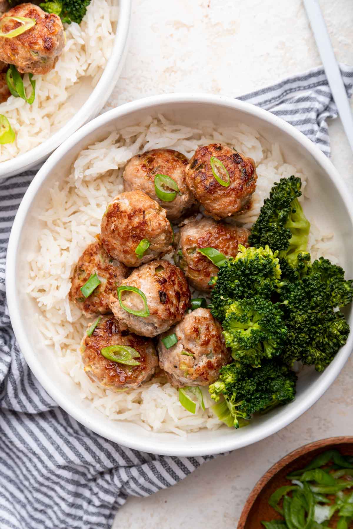 Overhead shot of pork meatballs over rice with broccoli in the bowl.