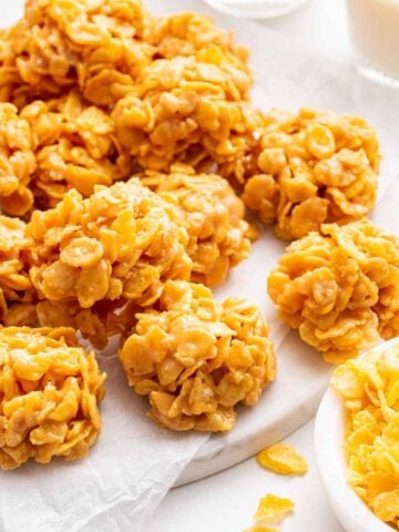 Vertical image of cornflake cookies on white cutting board.