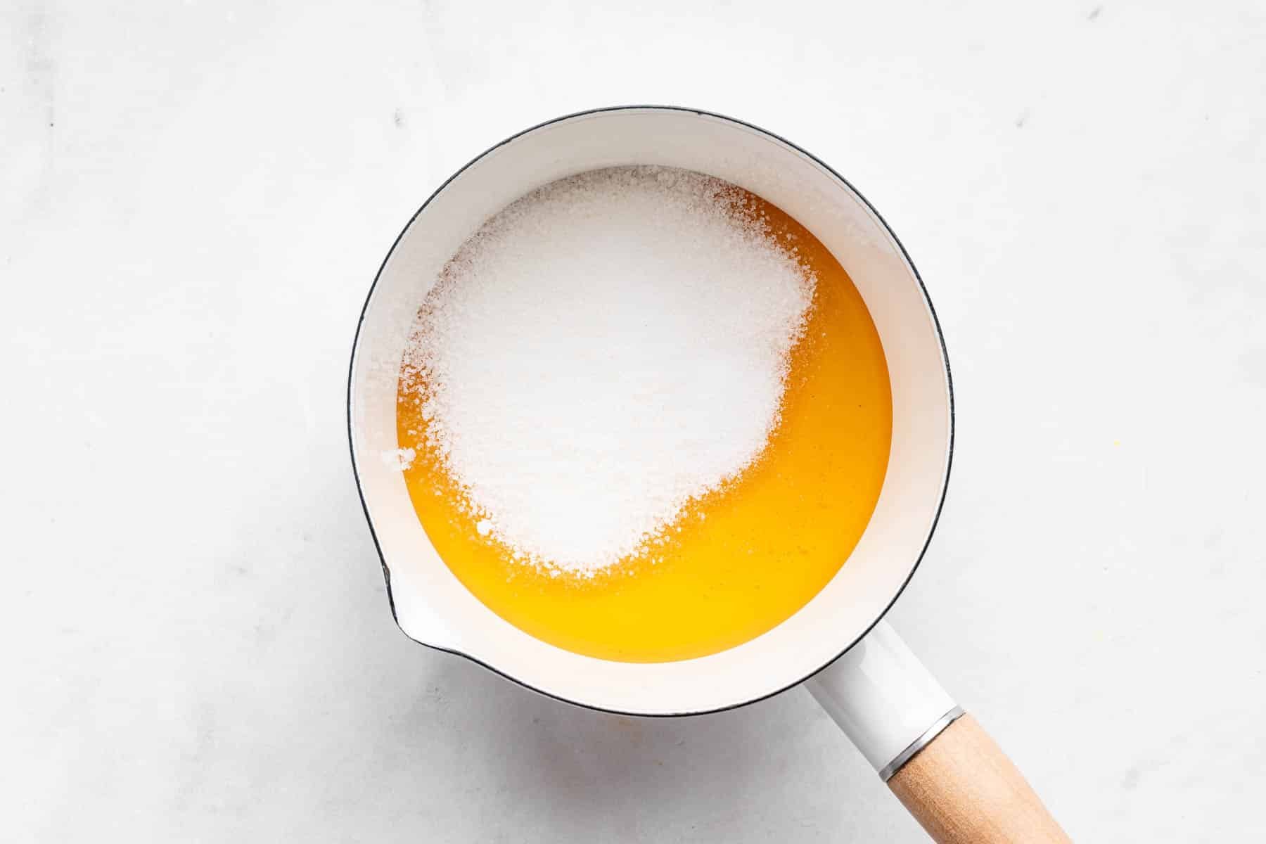Small white saucepan with honey and sugar inside.